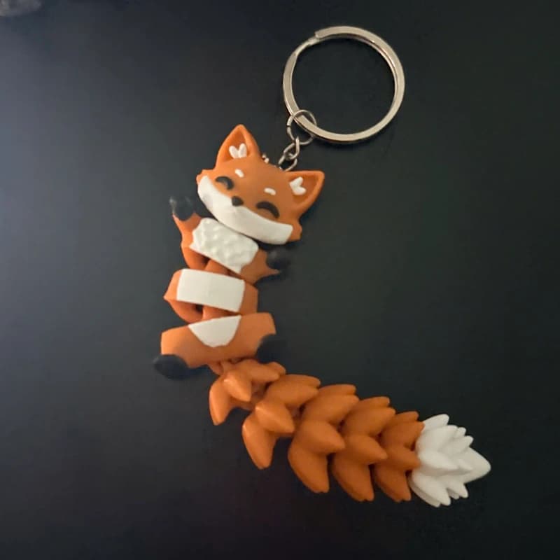 Móc khoá cáo flexi màu cam cầm trên tay, thấy rõ các khớp nối