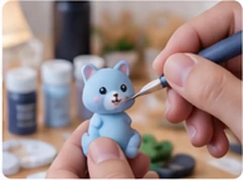 Tay đang tô màu thủ công cho một mô hình mèo xanh in 3D